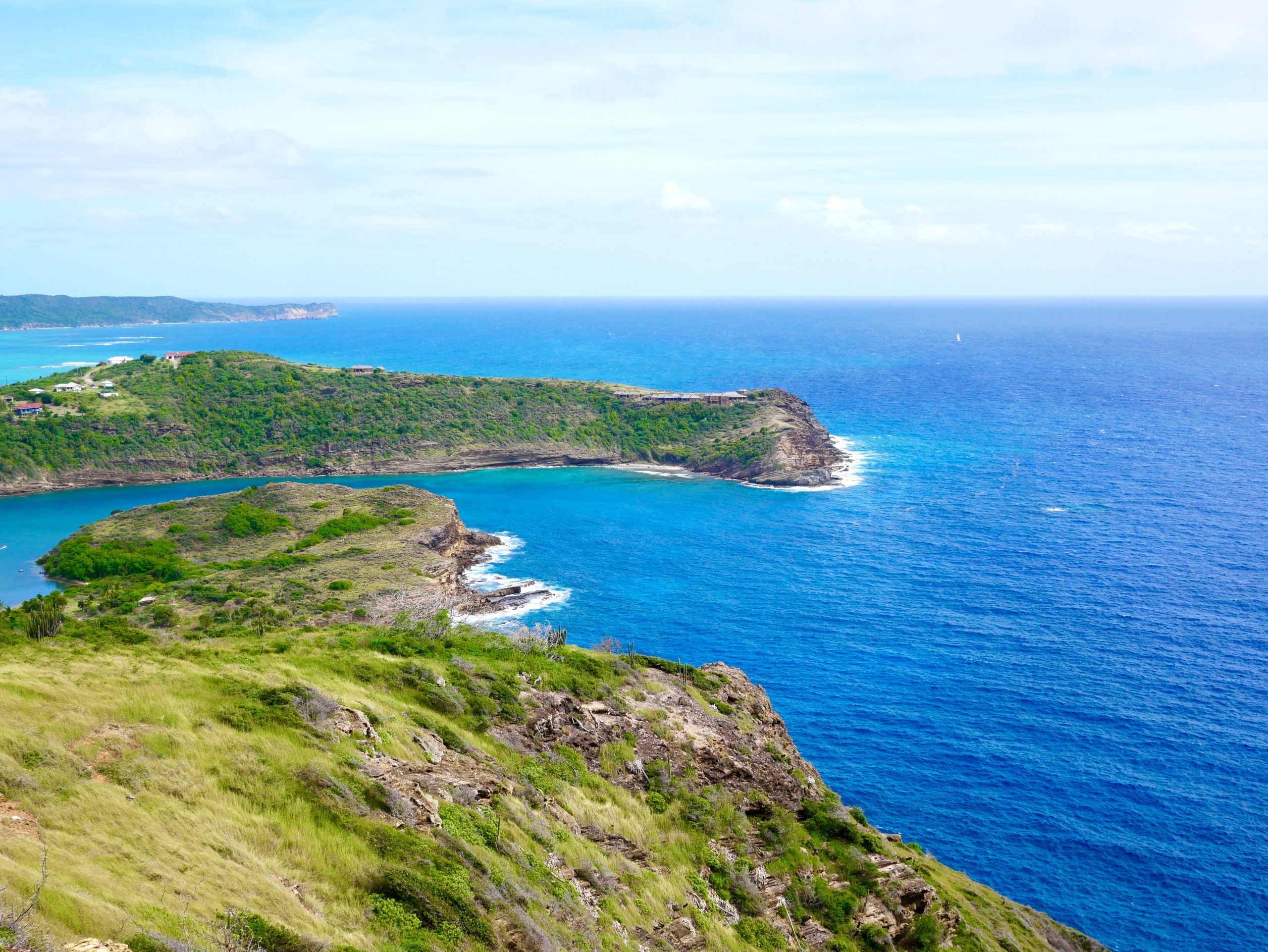 Aerial view of a lush green island coastline meeting turquoise ocean waters, representing a Small Island Developing State